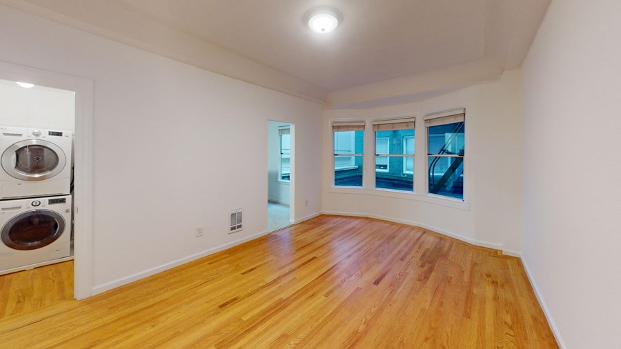 a living room with a washing machine and a wood floor